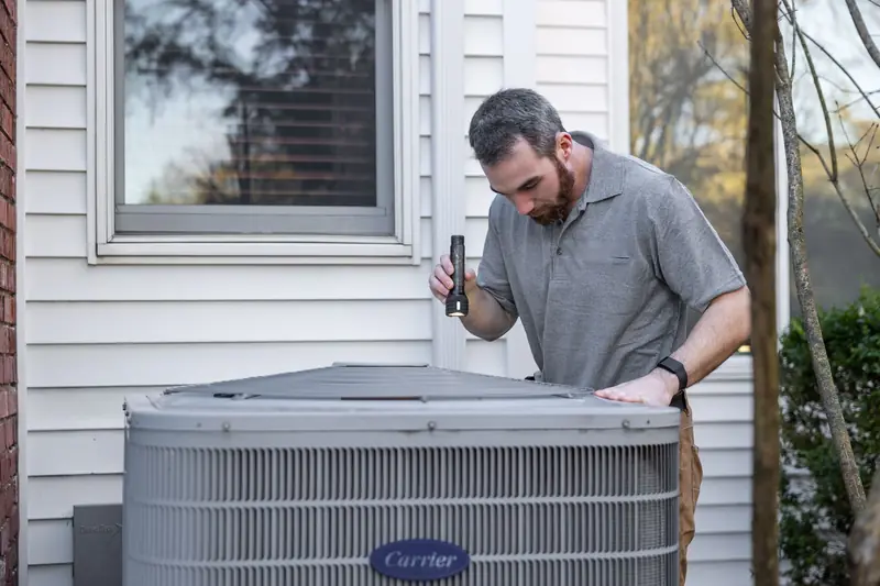 HVAC technician inspecting an outdoor air conditioner condenser beside a house